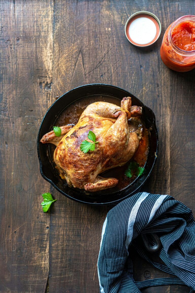A golden roast chicken in a black cast-iron skillet