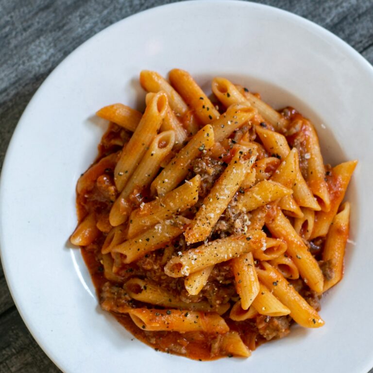Penne pasta in a creamy tomato sauce on a white plate