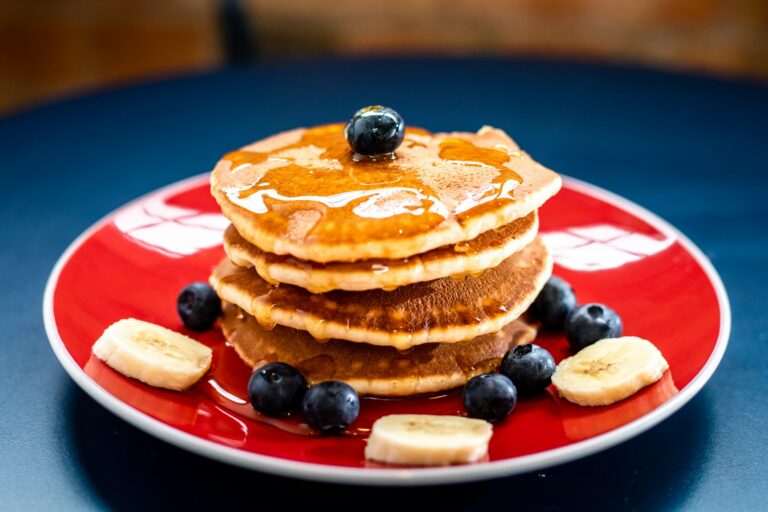 A stack of golden pancakes topped with blueberries, banana slices and maple syrup