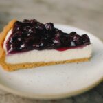 A slice of cheesecake with a glossy blueberry topping