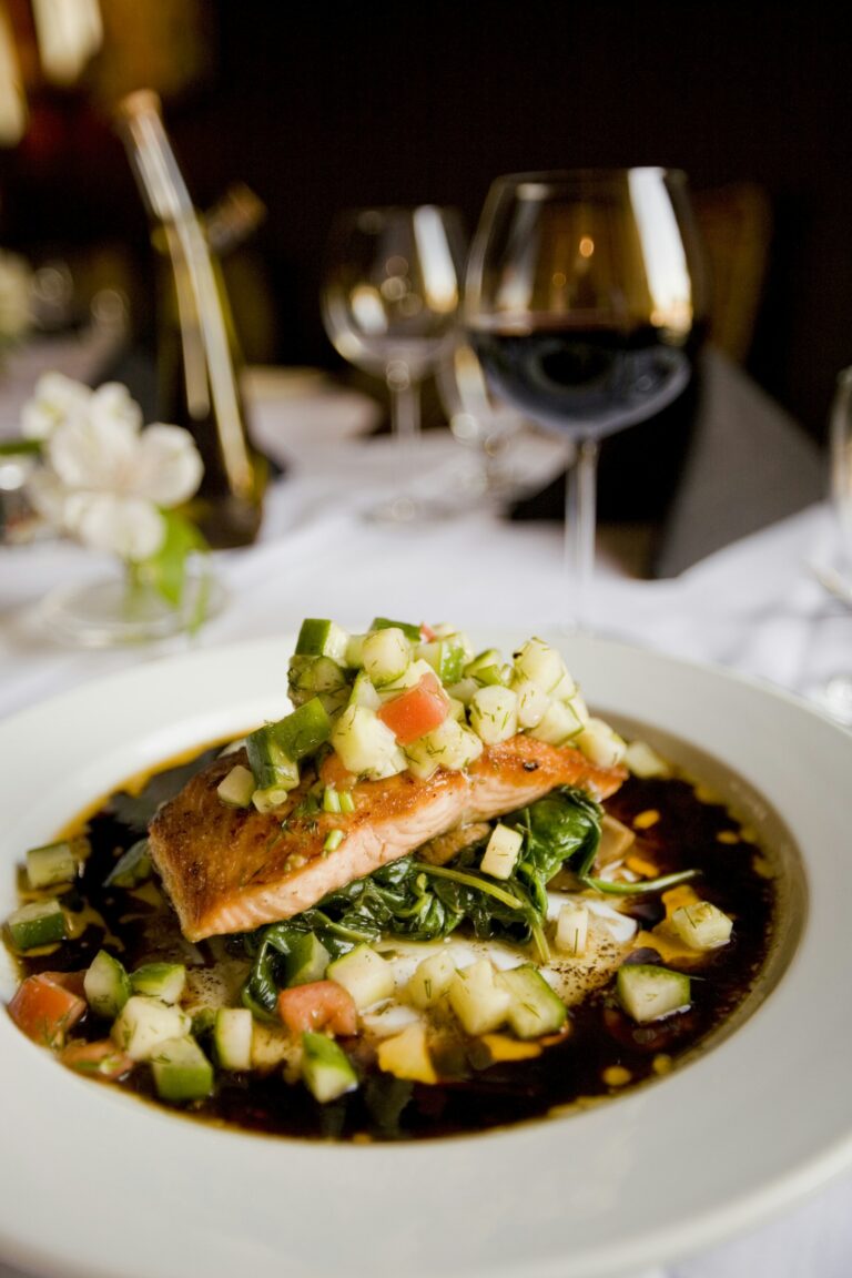 A seared salmon fillet topped with fresh salsa on a bed of greens